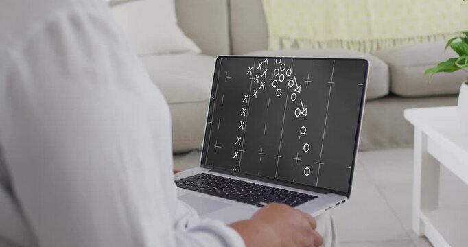 Woman in white top sitting on sofa watching Xs and Os appearing on laptop, studying play
