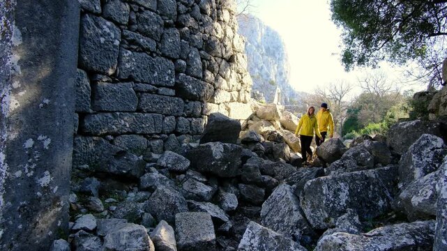 Young travelers discover ancient amphitheater and ruins of Termessos. Walking, climbing, enjoying view and ancient history in warm Turkish light.
