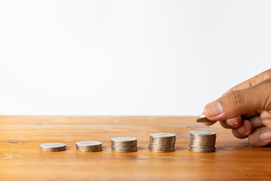 Hand putting coin on stack representing money savings and growth