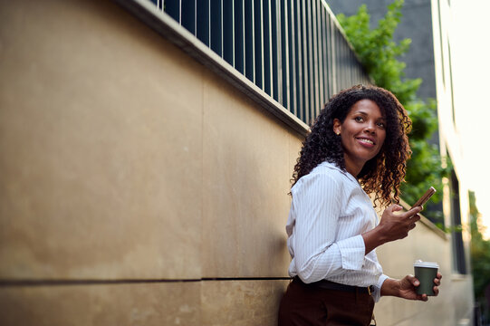 African American Business Woman Smiling With Smartphone And Coffee On Urban Morning Commute