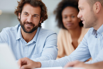Fototapeta premium Three professionals collaborate around a laptop in a bright office. The man in focus smiles gently, showing engagement and confidence. Woman and another man sit behind, focused on the shared task