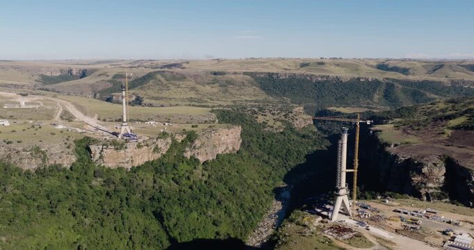 Panning wide aerial view of the construction of Msikaba Bridge in the Eastern Cape, South Africa. It will span 580 meters across the Msikaba River gorge and stand 194 meters high. Economic development