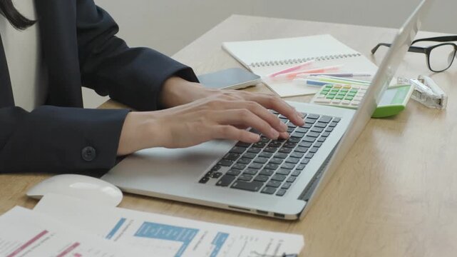 Close-up of Japanese businesswoman hands working on computer by window