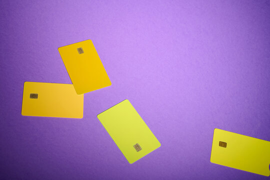 Closeup of yellow and orange debit cards with a microchip on a purple table