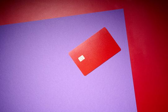 Closeup of a red debit card with a microchip on a purple table