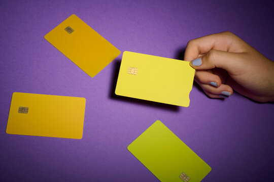Closeup of a teenage girl's hand depositing a yellow debit card on a purple table.