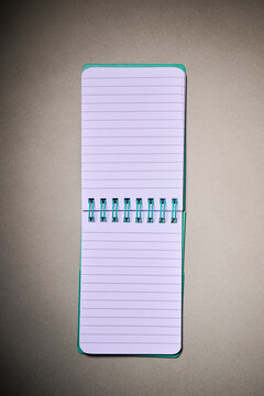 Closeup of a small spiral notebook open on a desk.