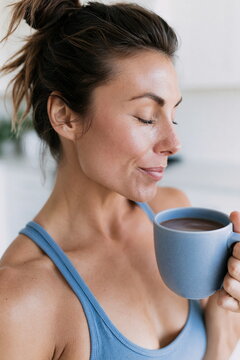 Thoughtful Woman with Raw Skin Texture Enjoying a Cup of Herbal Tea in a Sunlit Kitchen, Creating a Warm and Inviting Atmosphere of Reflection