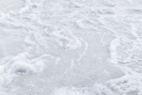 Pale white snow and ice create a delicate frozen surface with swirling frost patterns and subtle texture, evoking cold, calm, minimal winter feelings and abstract natural details