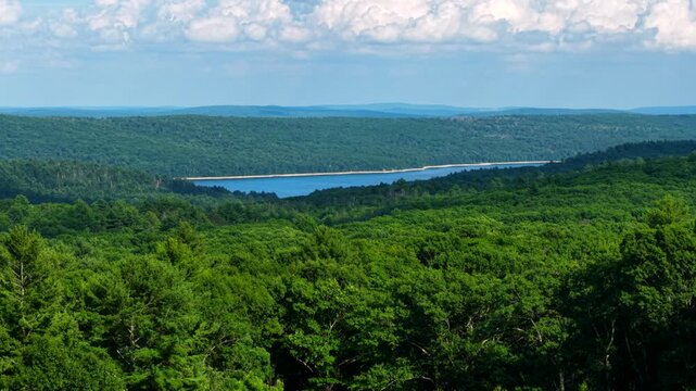 Aerial ascend reveals Quabbin Reservoir in Massachusetts from Pelham Overlook, exposed shoreline band due to drought conditions and water scarcity in the Summer