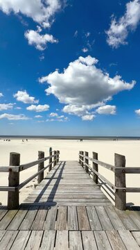 wooden pier on the beach with blue sky and white clouds