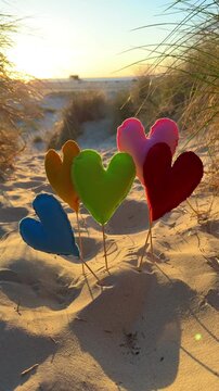 beautiful colorful hearts in the dunes near the sea in sunset light	

