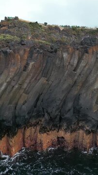 rocks and stone pattern under sea waves with white foam, natural gray cliff, rocky surface or texture, 4k vertical video