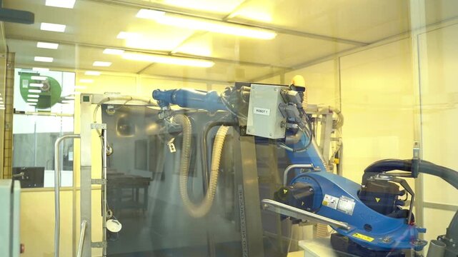Industrial robot arm working inside a glass enclosed automation cell