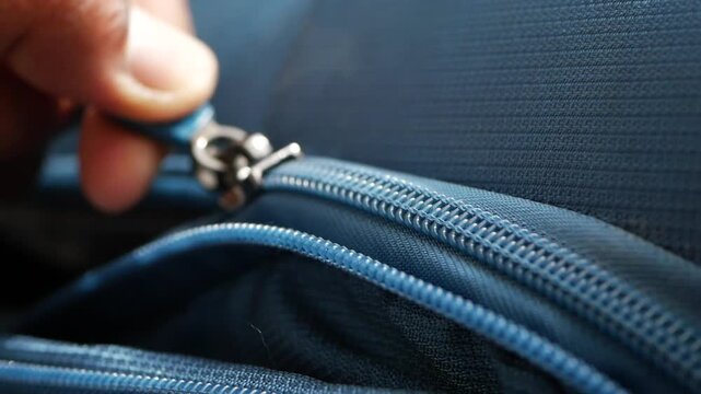 Hand Unzipping a Blue Fabric Suitcase