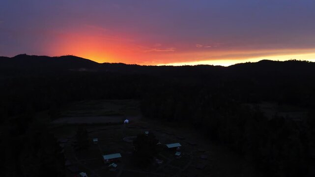 Aerial Drone Shot of Off-Grid Camp Beneath Fiery Sunset Horizon, Sillar de los Indios, Constanza Dominican Republic