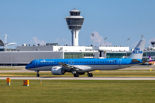 Ein Embraer E190 von KLM Cityhopper (Kennung PH-NXJ) rollt bei sonnigem Sommerwetter auf dem Vorfeld des Flughafens M&uuml;nchen. 
