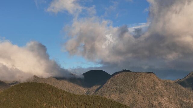 Cinematic aerial drone footage of receding mountain ridgelines fading into hazy silhouette under a dramatic, cloud-heavy sunset sky in Constanza, Dominican Republic