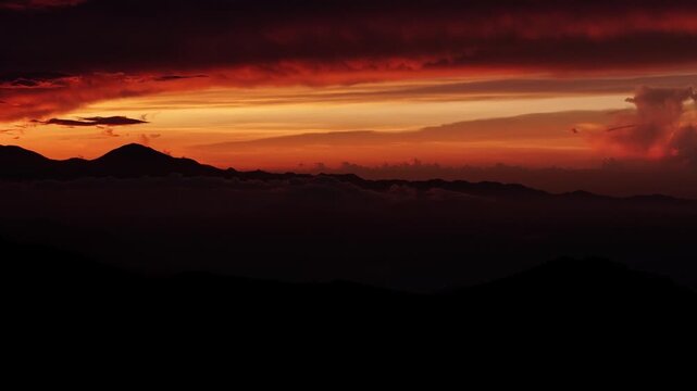 Cinematic aerial drone footage of a breathtaking sunset over the mountain landscape of Valle Nuevo National Park in Constanza, Dominican Republic. Dramatic orange sky, glowing horizon