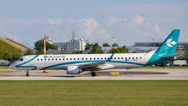 Ein Embraer E195 der Air Dolomiti (Lufthansa Group) rollt bei sonnigem Sommerwetter auf dem Rollfeld. 