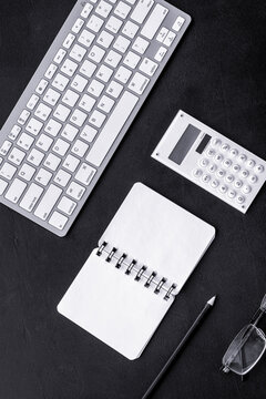 Office desk in order. Geometry. Computer keyboard and office supplies, glasses on black background top view