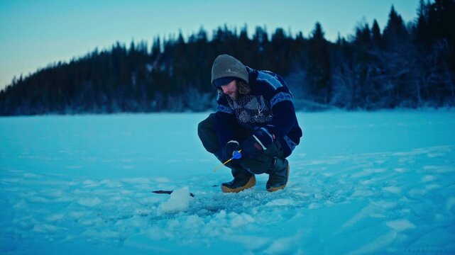 A Man Sitting On A Frozen Lake While Ice Fishing During The Winter Season. Close-up Shot