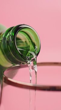 A green bottle tips to pour soft dinks into a glass .