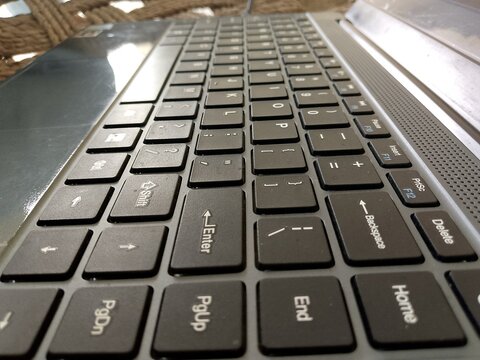Close up low angle perspective of a black laptop keyboard featuring detailed keys and function buttons for digital computing tasks and professional work environments in a minimalist modern office