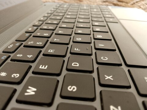 Extreme close up perspective of a modern black laptop keyboard featuring a standard qwerty layout design for professional computing and digital communication tasks in a bright indoor office setting