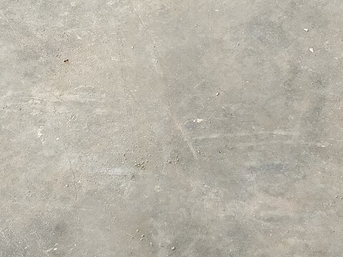 A high angle close up view of a raw grey concrete floor surface featuring natural imperfections scratches and dusty texture details for a minimalist industrial design background with presents top