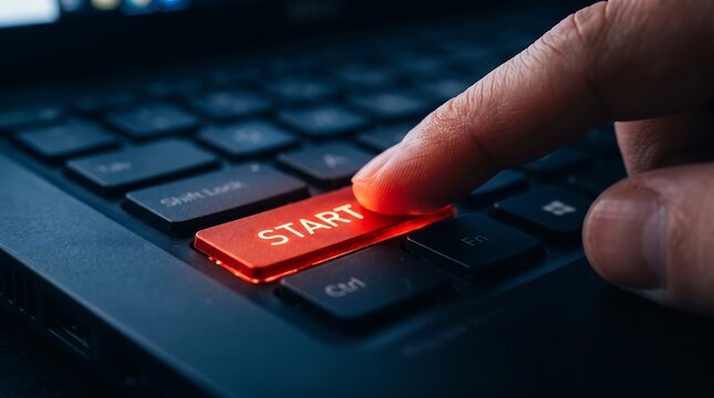Close up of finger pressing illuminated start button on professional laptop keyboard representing software launch or system boot for business and corporate technology editorial themes