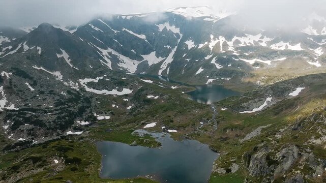Seven Rila Lakes panoramic aerial drone view glacial mountain lakes with snow patches and green slopes Rila National Park Bulgaria summer hiking travel destination background.