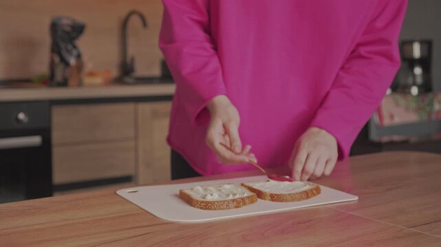 Spread mayonnaise on bread with a spoon to make sandwiches. Making sandwiches at home.