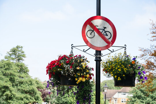 Corby, Northamptonshire, United Kingdom - July 15, 2026: No cycling sign with colorful hanging flower baskets in public park