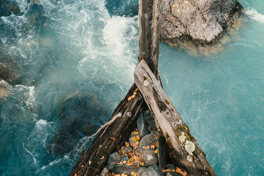 Wooden bridge piers and crystal clear stream in Kanas, Xinjiang, China, surrounded by lush forest and mountains, serene natural landscape