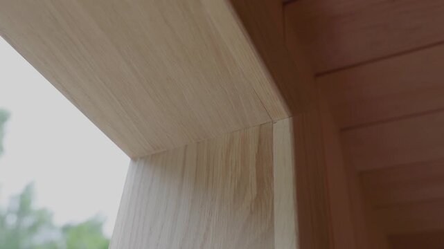 Close-up of a precision-crafted wooden house window frame corner with natural wood grain and soft daylight. Shallow depth of field with blurred outdoor background and copy space