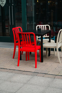 Corby, Northamptonshire, United Kingdom - July 15, 2026: Empty outdoor cafe tables and red chairs in modern shopping center