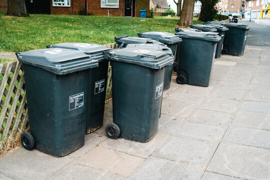 Corby, Northamptonshire, United Kingdom - July 15, 2026: Residential wheelie bins lined up on neighborhood sidewalk for waste collection