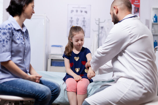 Girl having pains because of arm during medical check-up in hospital office. Healthcare physician specialist in medicine providing health care services treatment examination.