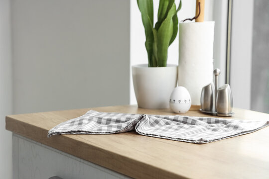 Kitchen counter with a checkered towel, egg timer, salt and pepper shakers, and a potted plant