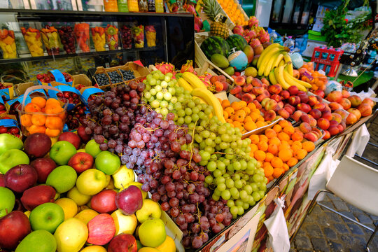 Abundant and colorful display of fresh organic fruits including grapes, apples, and bananas at an outdoor market stall
