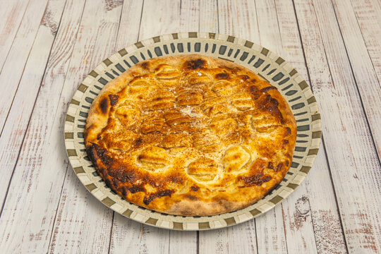 Sweet Banana Dessert Pizza with Cinnamon Dusting on Patterned Ceramic Plate