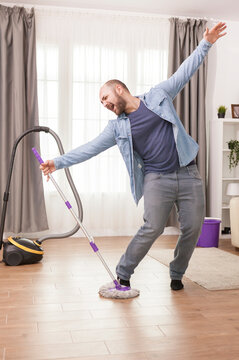 Cheerful man dances during cleaning chores, cheerful man dancing with mop while cleaning the floor, connecting home improvement, household work and domestic maintenance.