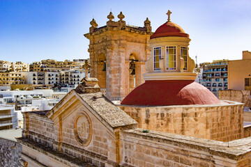 Historic limestone church with red dome above a Maltese town © Filandre