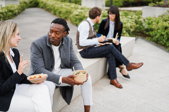 Multiracial business people doing lunch break outside during fall time - Outdoor meeting and entrepreneur concept - Focus on african man face