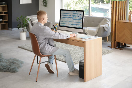 Young male programmer working with computer in modern home office