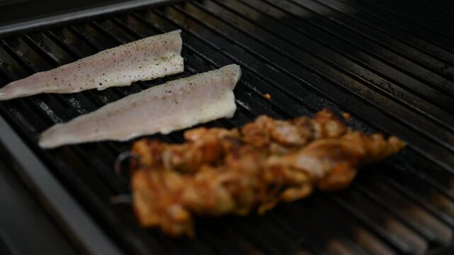Fish and meat skewers cooking on the grill.