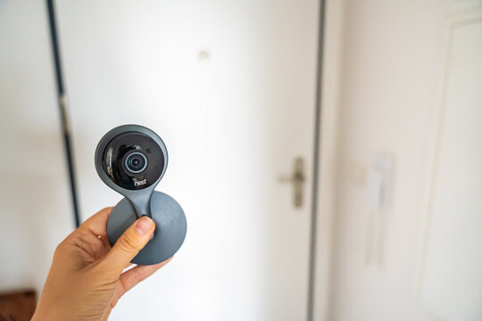 Prague, Czech Republic - June 30, 2026: Person holds Nest security camera in front of home entrance door. Smart home security concept for residential surveillance, installation and access monitoring
