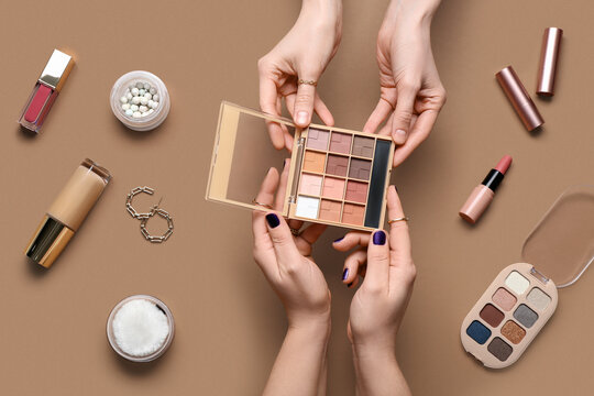Female hands with different decorative cosmetics and earrings on brown background