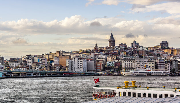 Istanbul, Turkey - September 23, 2014: Galata Tower rises above the Karakoy district skyline, with ferry boats crossing the Golden Horn in the foreground.